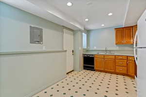 Kitchen with brown cabinets, recessed lighting, a sink, electric panel, and dishwasher