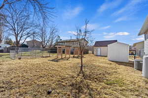 View of yard featuring cooling unit, a fenced backyard, an outbuilding, and a shed