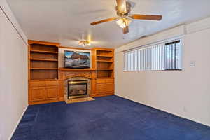 Unfurnished living room featuring visible vents, baseboards, ceiling fan, dark colored carpet, and a high end fireplace