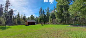 View of yard with an outdoor structure, a storage shed, and fence