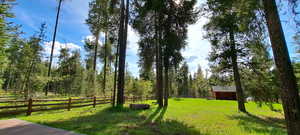 View of yard with a wooded view and fence