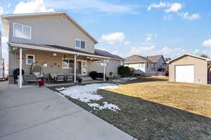 Back of house featuring a patio area, a detached garage, and a yard