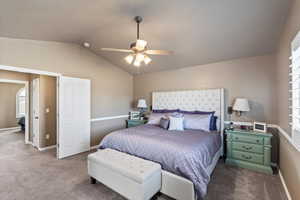 Carpeted bedroom with baseboards, vaulted ceiling, and a ceiling fan