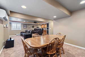 Carpeted dining space with recessed lighting, baseboards, a textured ceiling, and a wall mounted AC