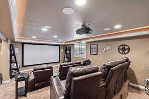 Cinema room with carpet, a tray ceiling, baseboards, and recessed lighting