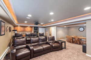 Carpeted cinema featuring baseboards, a baseboard heating unit, a tray ceiling, and recessed lighting