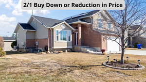 View of front of property with brick siding, a garage, a front lawn, driveway, and central AC