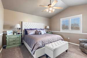 Bedroom with ceiling fan, vaulted ceiling, baseboards, and dark colored carpet