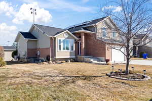 View of front of home featuring brick siding, concrete driveway, central AC unit, roof mounted solar panels, and a front lawn