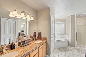 Full bathroom with a textured ceiling, a stall shower, and a sink