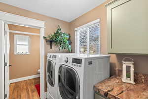 Laundry room featuring laundry area, baseboards, washer and dryer, and wood finished floors