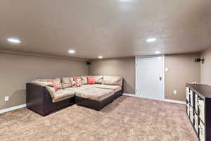 Living room with carpet, a textured ceiling, baseboards, and recessed lighting