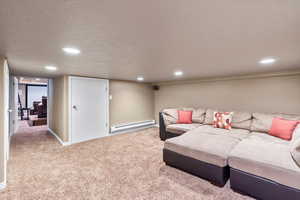 Carpeted living area featuring recessed lighting, baseboards, a textured ceiling, and baseboard heating