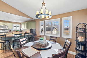 Dining space featuring lofted ceiling, recessed lighting, wood finished floors, baseboards, and an inviting chandelier