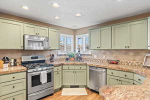 Kitchen featuring green cabinets, appliances with stainless steel finishes, and a sink