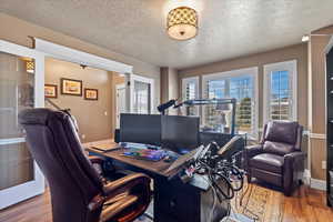 Office with a textured ceiling, baseboards, and wood finished floors