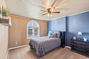 Carpeted bedroom with visible vents, a textured ceiling, a ceiling fan, and baseboards