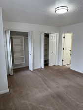 Unfurnished bedroom featuring carpet, two closets, and baseboards