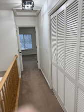 Hall featuring a textured ceiling, baseboards, and light colored carpet