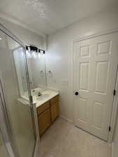 Bathroom featuring a stall shower, vanity, a textured ceiling, and tile patterned floors