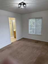 Carpeted spare room featuring a textured ceiling and baseboards