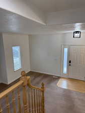Carpeted entrance foyer with a textured ceiling, visible vents, and baseboards