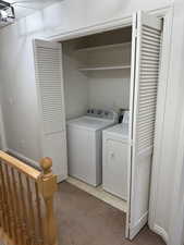 Washroom with laundry area, independent washer and dryer, and light colored carpet