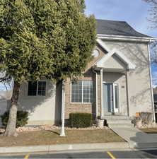 View of front of property with stucco siding, a shingled roof, and brick siding