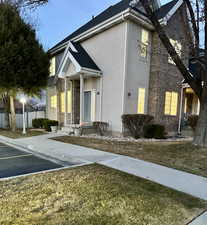 View of front of house with uncovered parking, brick siding, fence, and stucco siding