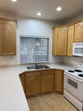 Kitchen featuring crown molding, light countertops, light wood-style flooring, a sink, and white appliances