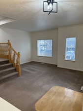 Interior space with stairs, baseboards, and a textured ceiling