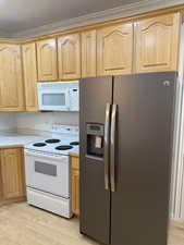 Kitchen with light wood-type flooring, white appliances, light brown cabinets, and light countertops