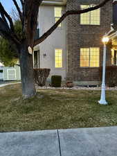 View of side of property featuring brick siding, a lawn, and stucco siding