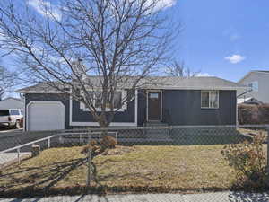 View of front of house with a garage, a front yard, brick siding, and a fenced front yard