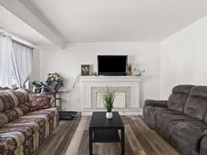 Living area with a fireplace with raised hearth and wood finished floors