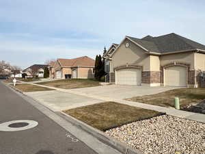 View of front of house with an attached garage, brick siding, concrete driveway, a residential view, and stucco siding