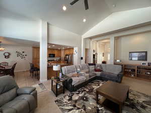 Living area with high vaulted ceiling, recessed lighting, ceiling fan with notable chandelier, light colored carpet, and baseboards