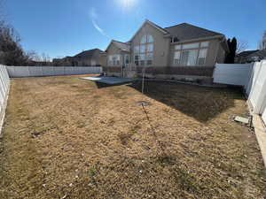 Back of house with brick siding, a patio, a fenced backyard, a yard, and stucco siding