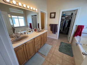 Full bath featuring a garden tub, a sink, and double vanity