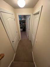 Hall with stairway, a textured ceiling, and light colored carpet