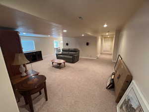 Carpeted living area featuring recessed lighting, visible vents, and baseboards