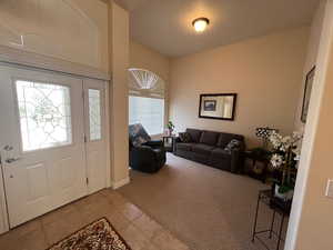 Foyer with carpet, vaulted ceiling, and tile patterned floors