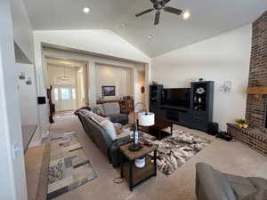 Living room featuring light carpet, a ceiling fan, vaulted ceiling, a fireplace, and recessed lighting