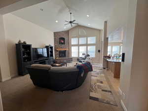 Living room with a textured ceiling, recessed lighting, a fireplace, baseboards, and vaulted ceiling