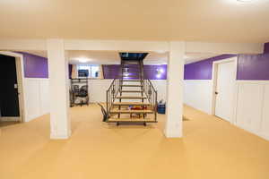 Finished basement featuring new carpet, wainscoting, and sunken play area