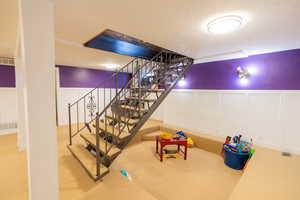 Finished basement featuring new carpet, wainscoting, and sunken play area