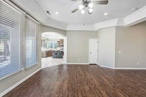 Unfurnished room featuring visible vents, arched walkways, a raised ceiling, and wood finished floors