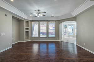 Spare room with arched walkways, a textured ceiling, wood finished floors, and a ceiling fan