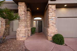 Property entrance with stone siding and an attached garage