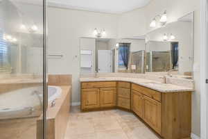 Full bathroom with double vanity, a garden tub, a shower stall, and a sink